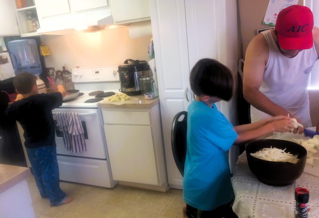 Family Preparing Dinner Together Father and two children preparing dinner together in the family kitchen