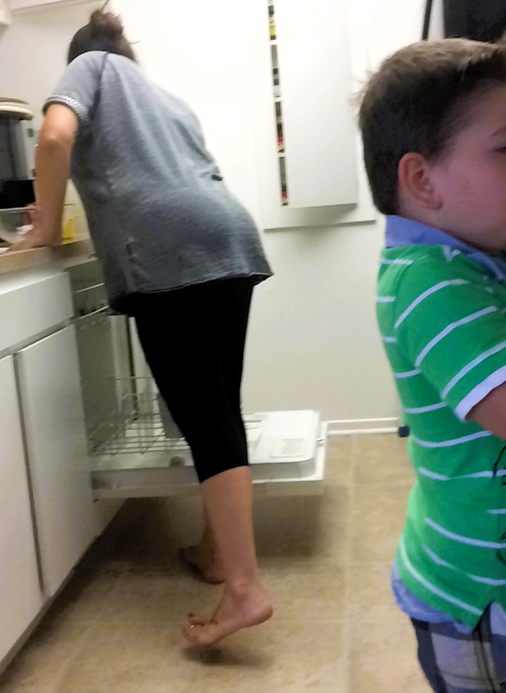 me cleaning kitchen with Gavin _2015 Mother unloading the dishwasher while her young son stands nearby, illustrating the invisible work of everyday family life.